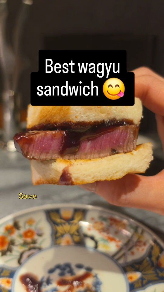 Hand holding a thick wagyu sandwich