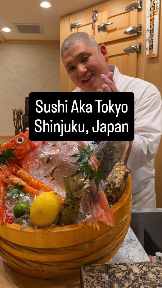Smiling sushi chef at Sushi Aka in Shinjuku with a tub of fresh seafood