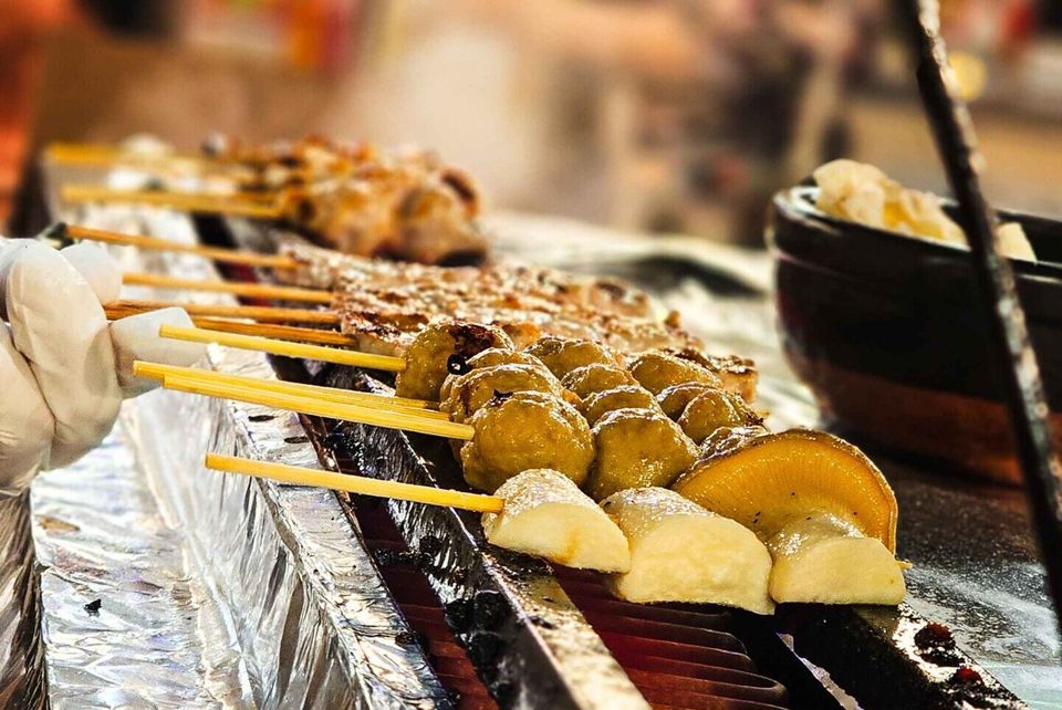 Skewers sizzling on a grill at a Tokyo street food stall